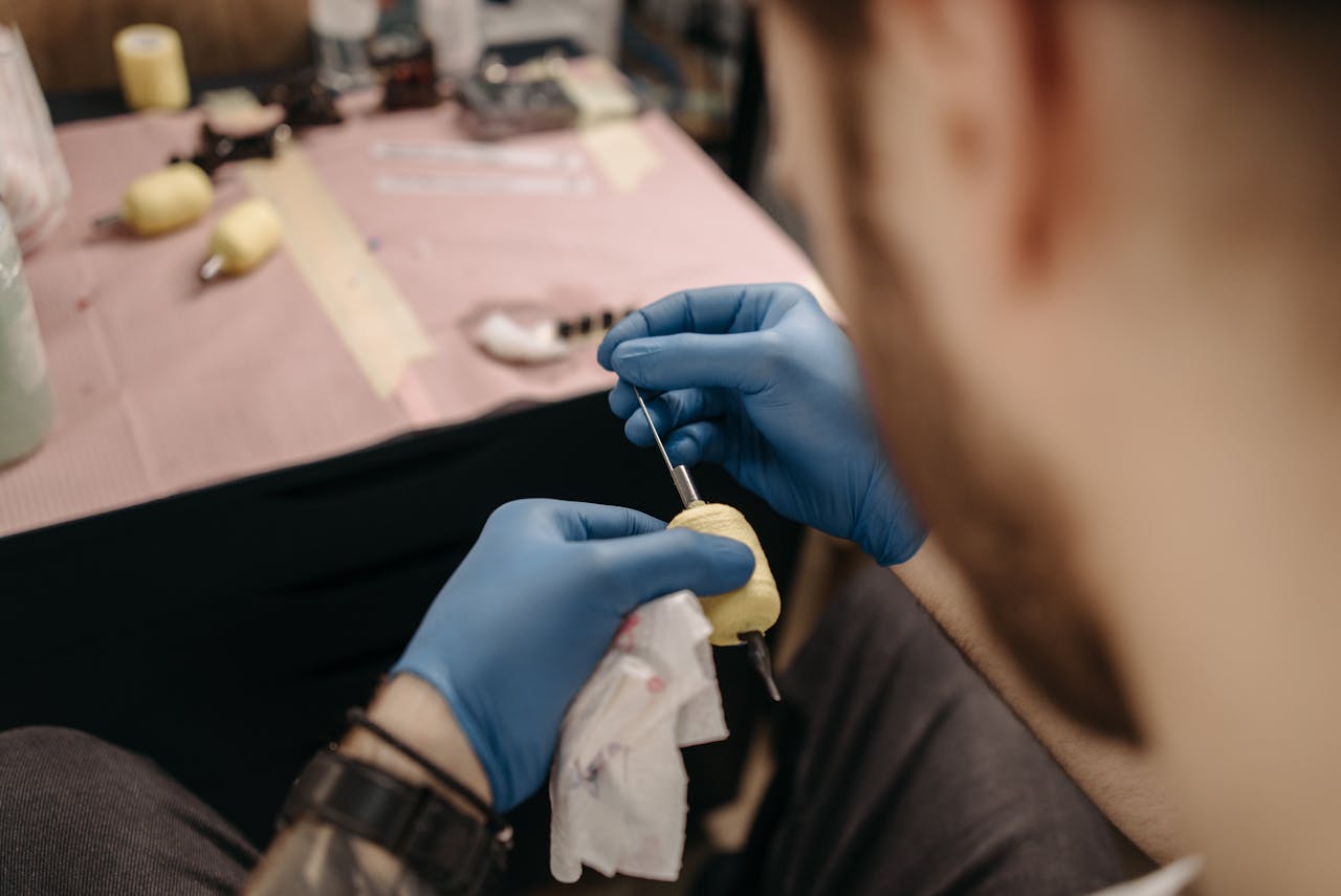 who-we-are Close-up of a tattoo artist setting up a tattoo machine in a studio setting with precision.